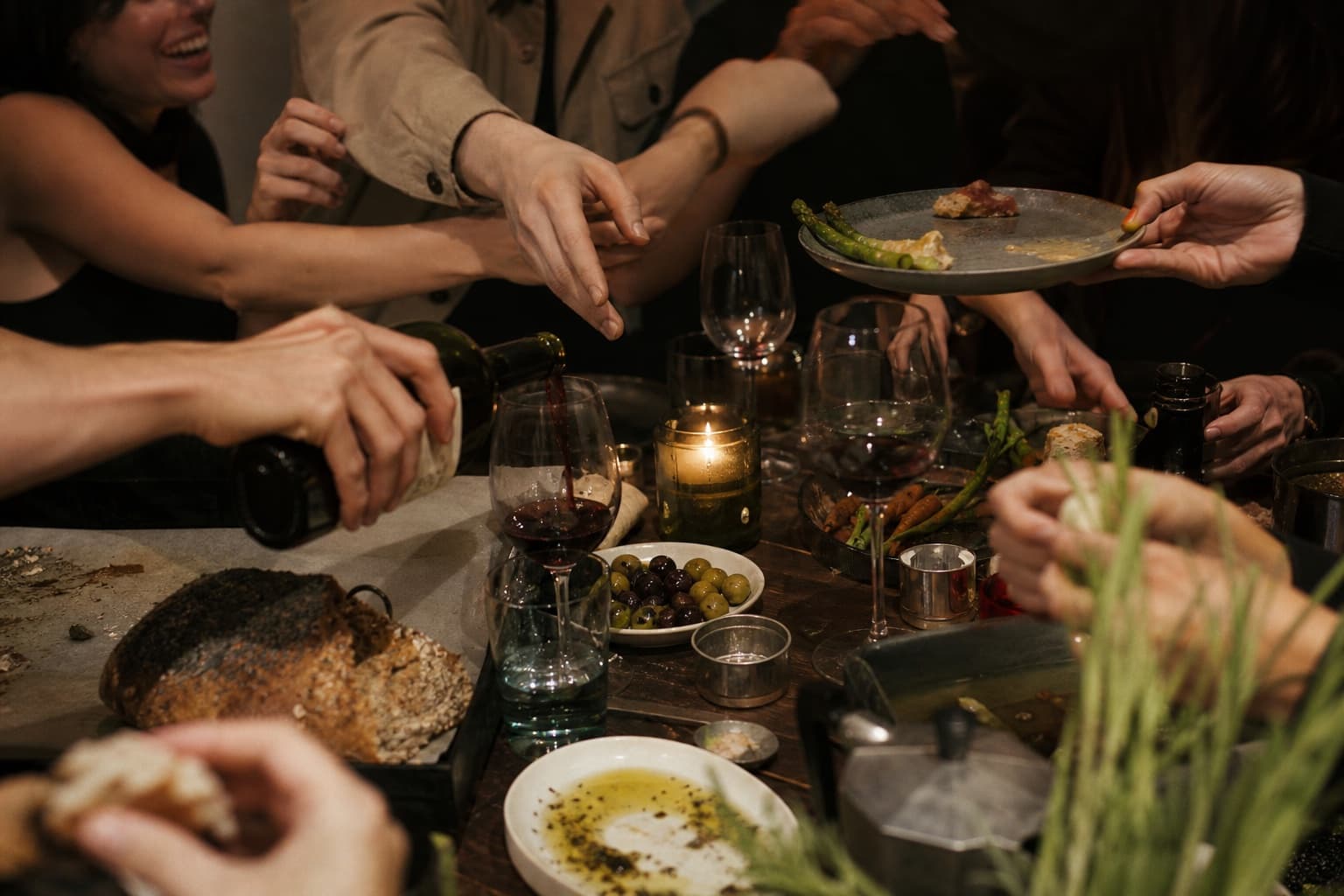 Una mesa viva con personas compartiendo pan, vino y comida
