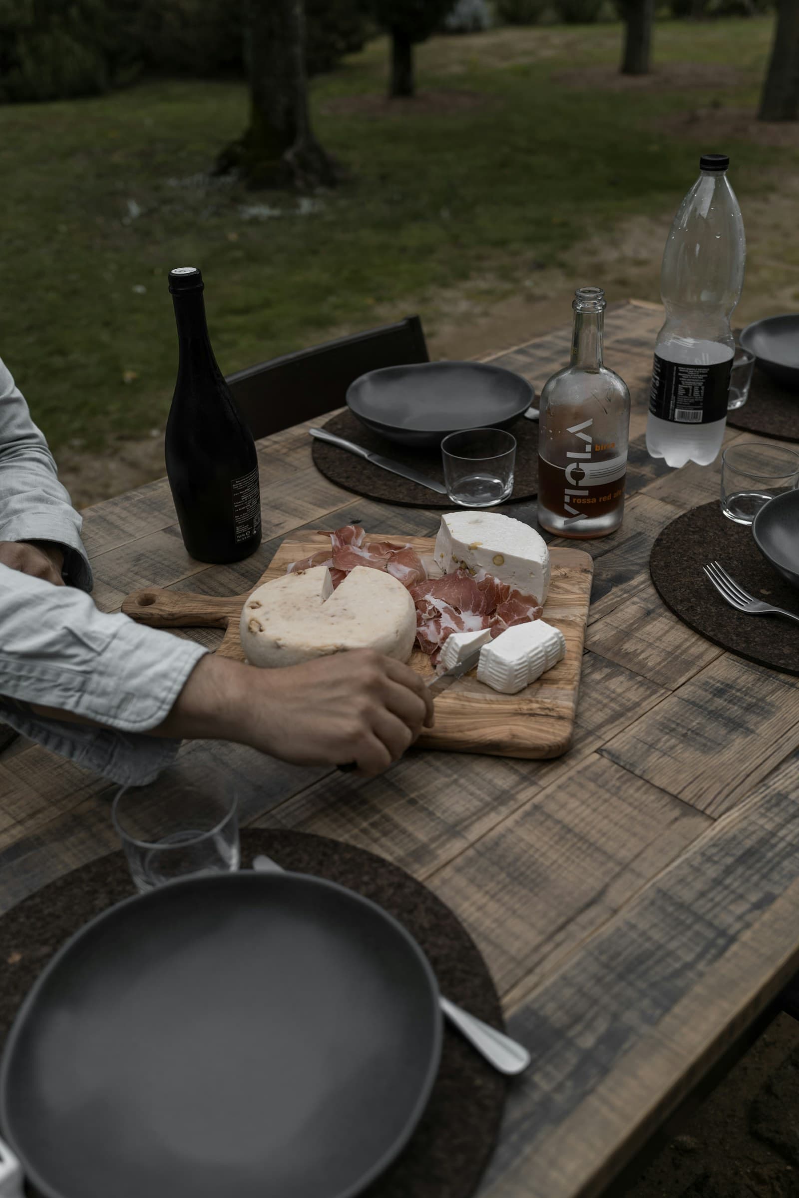 Mesa exterior con quesos y una botella lista para compartir